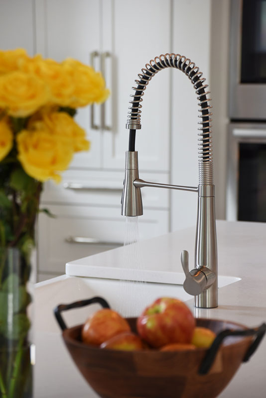 Kitchen remodel detail featuring faucet close-up, white granite countertops and cabinets